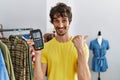 Young hispanic man holding dataphone and credit card at retail shop pointing thumb up to the side smiling happy with open mouth Royalty Free Stock Photo