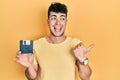 Young hispanic man holding floppy disk pointing thumb up to the side smiling happy with open mouth Royalty Free Stock Photo