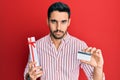 Young hispanic man holding gift and credit card depressed and worry for distress, crying angry and afraid Royalty Free Stock Photo