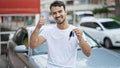 Young Hispanic Man Holding Key Of New Car Doing Thumb Up Gesture At Street