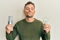 Young hispanic man holding lightbulb for inspiration and idea looking at the camera blowing a kiss being lovely and sexy Royalty Free Stock Photo