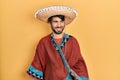 Young hispanic man holding mexican hat looking away to side with smile on face, natural expression Royalty Free Stock Photo