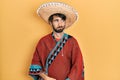 Young hispanic man holding mexican hat smiling looking to the side and staring away thinking Royalty Free Stock Photo