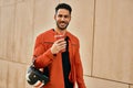 Young hispanic man holding motorcycle helmet and drinking coffee at the city Royalty Free Stock Photo