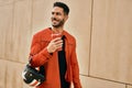 Young hispanic man holding motorcycle helmet and drinking coffee at the city Royalty Free Stock Photo