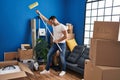 Young hispanic man holding paint roller dancing at new home Royalty Free Stock Photo