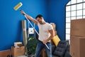 Young hispanic man holding paint roller dancing at new home Royalty Free Stock Photo