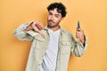 Young hispanic man holding pocket knife with angry face, negative sign showing dislike with thumbs down, rejection concept Royalty Free Stock Photo