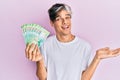 Young hispanic man holding russian 200 ruble banknotes celebrating achievement with happy smile and winner expression with raised