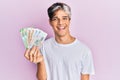 Young hispanic man holding russian ruble banknotes looking positive and happy standing and smiling with a confident smile showing