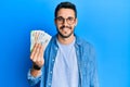 Young hispanic man holding russian ruble banknotes looking positive and happy standing and smiling with a confident smile showing