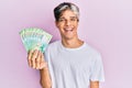 Young hispanic man holding russian 200 ruble banknotes looking positive and happy standing and smiling with a confident smile