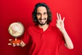 Young hispanic man holding small world ball doing ok sign with fingers, smiling friendly gesturing excellent symbol Royalty Free Stock Photo