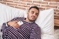 Young hispanic man holding smartphone lying on bed sleeping at bedroom Royalty Free Stock Photo