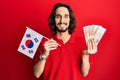 Young hispanic man holding south korea flag and won banknotes smiling with a happy and cool smile on face Royalty Free Stock Photo