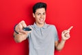 Young hispanic man holding television remote control smiling happy pointing with hand and finger to the side Royalty Free Stock Photo