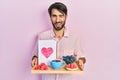 Young hispanic man holding tray with breakfast food and heart draw winking looking at the camera with sexy expression, cheerful Royalty Free Stock Photo