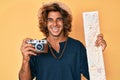 Young hispanic man holding vintage camera and city map smiling and laughing hard out loud because funny crazy joke Royalty Free Stock Photo