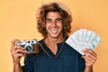 Young hispanic man holding vintage camera and dollars smiling and laughing hard out loud because funny crazy joke Royalty Free Stock Photo