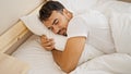 Young hispanic man hugging pillow lying on bed sleeping at bedroom Royalty Free Stock Photo