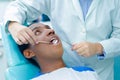 Young hispanic man lying in chair receiving dental treatment with mouth open, dentist hands wearing gloves holding tools Royalty Free Stock Photo