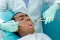 Young hispanic man lying in chair receiving dental treatment with mouth open, dentist hands wearing gloves holding tools Royalty Free Stock Photo