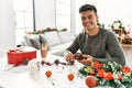 Young hispanic man make handsmade christmas decoration at home Royalty Free Stock Photo