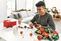 Young hispanic man make handsmade christmas decoration at home Royalty Free Stock Photo