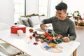 Young hispanic man make handsmade christmas decoration at home Royalty Free Stock Photo