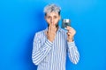 Young hispanic man with modern dyed hair holding floppy disk covering mouth with hand, shocked and afraid for mistake Royalty Free Stock Photo