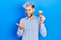 Young hispanic man with modern dyed hair holding floppy disk pointing thumb up to the side smiling happy with open mouth Royalty Free Stock Photo