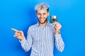 Young hispanic man with modern dyed hair holding floppy disk smiling happy pointing with hand and finger to the side Royalty Free Stock Photo