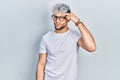 Young hispanic man with modern dyed hair wearing white t shirt and glasses pointing unhappy to pimple on forehead, ugly infection Royalty Free Stock Photo