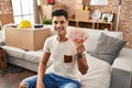 Young hispanic man moving to a new home holding shekels looking positive and happy standing and smiling with a confident smile Royalty Free Stock Photo