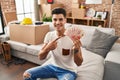 Young hispanic man moving to a new home holding shekels smiling happy pointing with hand and finger Royalty Free Stock Photo