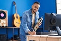 Young hispanic man musician composing song holding trumpet at music studio Royalty Free Stock Photo