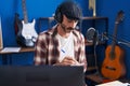 Young hispanic man musician listening to music composing song at music studio Royalty Free Stock Photo