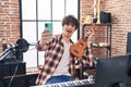 Young hispanic man musician making selfie by the smartphone holding ukelele at music studio