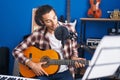 Young hispanic man musician singing song playing classical guitar at music studio Royalty Free Stock Photo