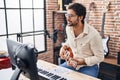 Young hispanic man musician singing song playing ukulele at music studio Royalty Free Stock Photo