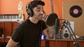 Young hispanic man musician smiling confident singing song at music studio