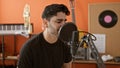 Young hispanic man musician smiling confident singing song at music studio