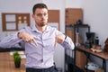 Young hispanic man at the office pointing down looking sad and upset, indicating direction with fingers, unhappy and depressed Royalty Free Stock Photo