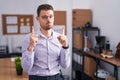 Young hispanic man at the office pointing up looking sad and upset, indicating direction with fingers, unhappy and depressed Royalty Free Stock Photo