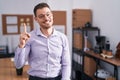 Young hispanic man at the office showing and pointing up with finger number one while smiling confident and happy Royalty Free Stock Photo