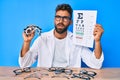 Young hispanic man with optometry glasses and paper with letters in shock face, looking skeptical and sarcastic, surprised with Royalty Free Stock Photo