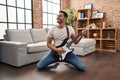 Young hispanic man playing electrical guitar with knees on floor at home Royalty Free Stock Photo