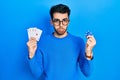 Young hispanic man playing poker holding casino chips and cards depressed and worry for distress, crying angry and afraid Royalty Free Stock Photo