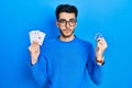 Young hispanic man playing poker holding casino chips and cards relaxed with serious expression on face Royalty Free Stock Photo