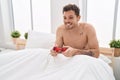 Young hispanic man playing video game sitting on bed at bedroom Royalty Free Stock Photo